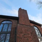 Completed gutter and downspout system on brick home in Dayton Ohio with chimney and large windows