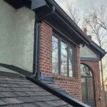 Black aluminum gutter and downspout installation on Dayton Ohio home with asphalt shingle roof and brick exterior