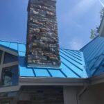 Blue standing seam metal roof installation in Lake Lorelei Ohio with stone chimney detail