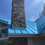 Blue standing seam metal roof installation in Lake Lorelei Ohio with stone chimney detail
