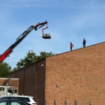 Roofing crew installing shingles on West Clermont School gym during school roof replacement in Batavia Ohio