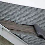 Roof with missing shingles exposing underlayment and decking on residential home