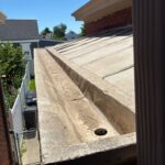 Close-up of deteriorated box gutter showing aging coating and drainage opening before restoration in Bellevue, Kentucky.