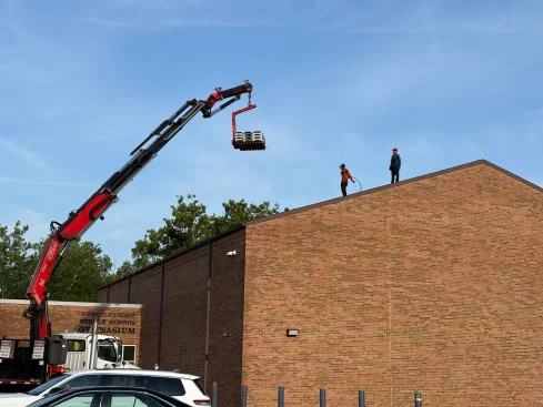 Roofing crew installing shingles on West Clermont School gym during school roof replacement in Batavia Ohio